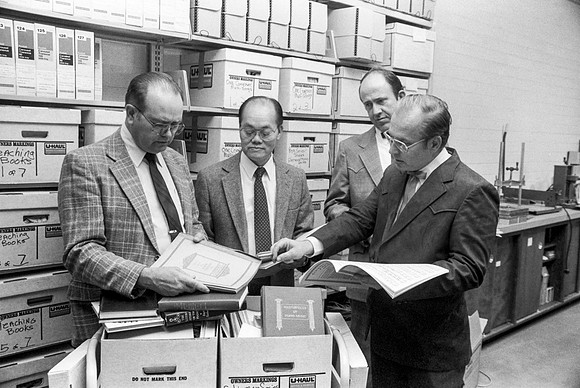 Faculty members looking through archieved books