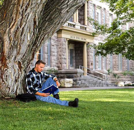 Ricks College student studying under a tree in front of the Spori building