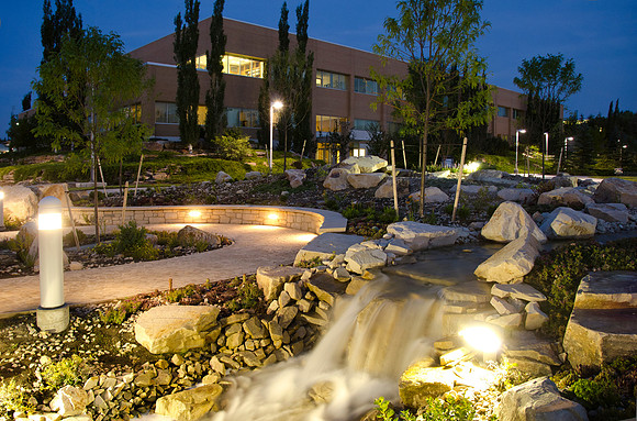 A water feature is lit up at night outside the Spencer W. Kimball Building.