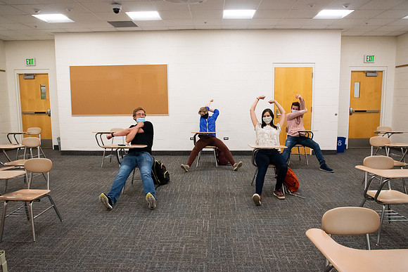 Examples of students staying safe and healthy during the COVID-19 pandemic by social distancing, following pathway arrows, and wearing face masks.