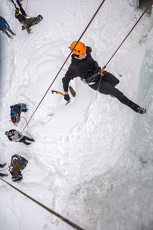 Davin Lybbart climbing on the ice face while Dana Mitchell belays.