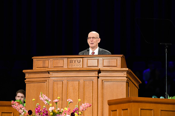 Elder Kyle S. McKay address students of BYU-Idaho in the I-Center. Other students and Henry J. Eyring assist in the Devotional.