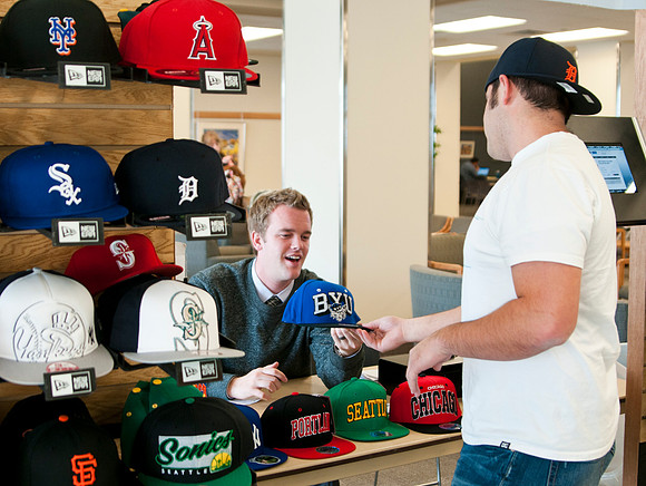 Kellen Heiner, student from the IBC Business Class talks with Erick Green, a student at BYU-Idaho, about buying a baseball cap in the MC Building.
