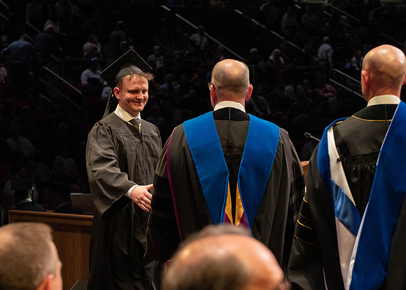 Students graduate and walk to receive their diplomas during convocation in the College of Physical Sciences and Engineering.