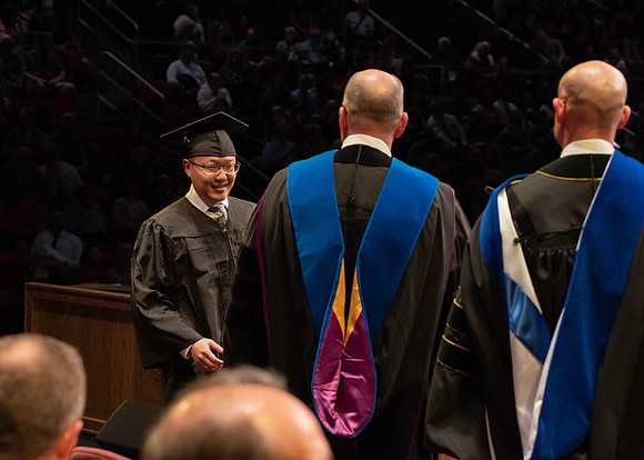 Students graduate and walk to receive their diplomas during convocation in the College of Physical Sciences and Engineering.