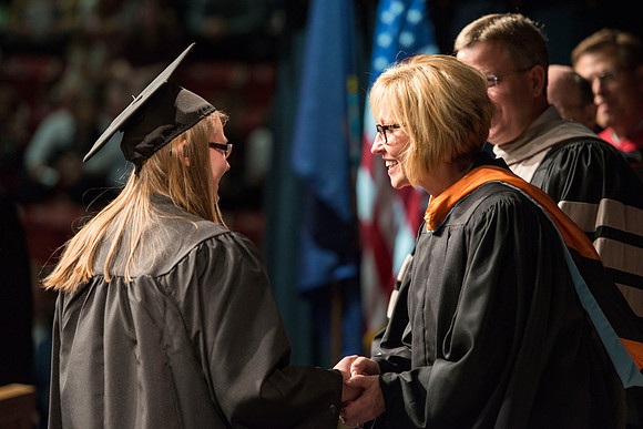 Karla A. LaOrange, Department Chair of Teacher Education, shakes hands with a student before receiving her diploma.