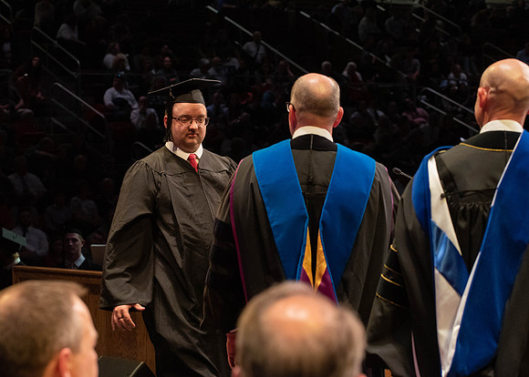 Students graduate and walk to receive their diplomas during convocation in the College of Physical Sciences and Engineering.