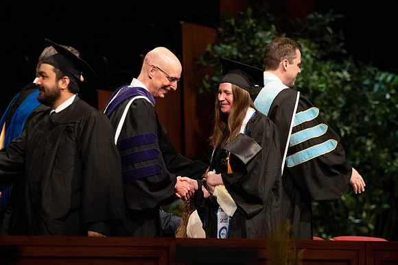 Students graduate and walk to recieve their diplomas during convocation in the College of Business and Communications.