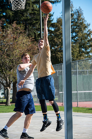 Jacob Kaiser (in yellow) playing basketball, one on one with Jacob Madsen at Smith Park in Rexburg, Idaho.