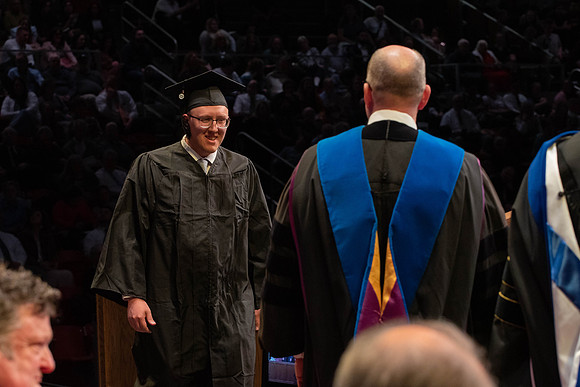Students graduate and walk to receive their diplomas during convocation in the College of Physical Sciences and Engineering.
