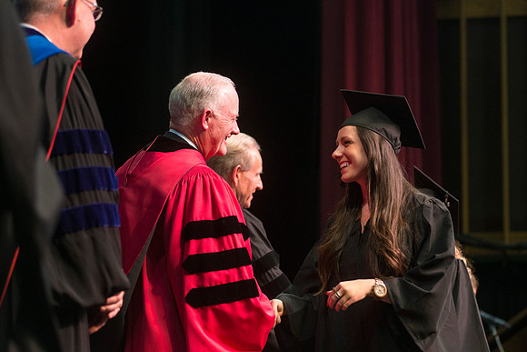 Elder W. Craig Zwick and President Kim B. Clark award diploma covers to graduates in the College of Business and Communication.