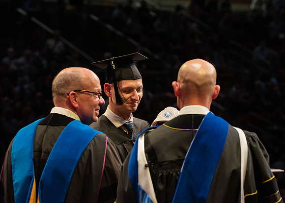 Students graduate and walk to receive their diplomas during convocation in the College of Physical Sciences and Engineering.
