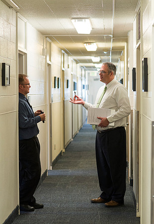 University Relations, Arnold Thiebaud, Creative Services Manager and Jeff Dunster, Web Communications Coordinator chat in the hallway of Biddulph Hall.