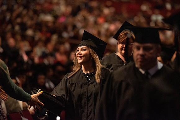 Students graduate and walk to recieve their diplomas during convocation in the College of Business and Communications.