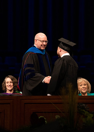 Students graduate and walk to recieve their diplomas during convocation in the College of Business and Communications.