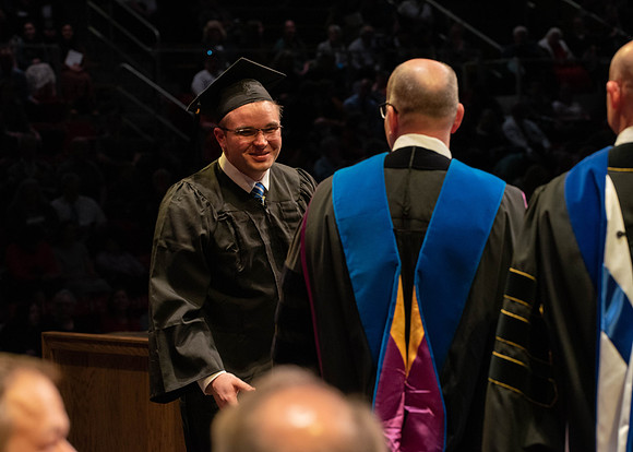Students graduate and walk to receive their diplomas during convocation in the College of Physical Sciences and Engineering.