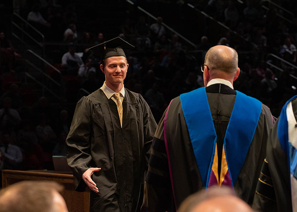 Students graduate and walk to receive their diplomas during convocation in the College of Physical Sciences and Engineering.