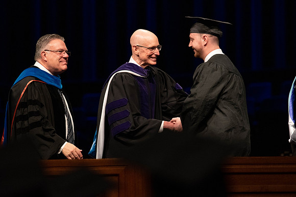Students graduate and walk to recieve their diplomas during convocation in the College of Business and Communications.