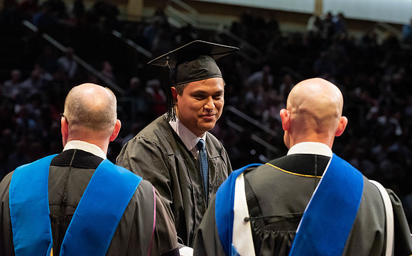 Students graduate and walk to receive their diplomas during convocation in the College of Physical Sciences and Engineering.