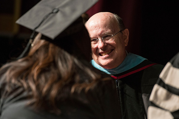 Elder Cook smiles as he shakes hands with a graduate during convocation.