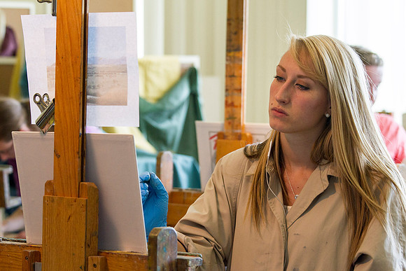 A student in Brother Bodily's Painting class concentrates on painting her landscape during class in the 2014 Spring Semester in the Spori Building.