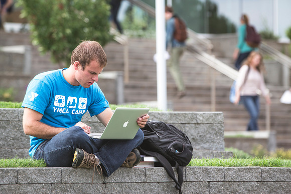 A man works on his laptop in the ampitheater on the first day of school