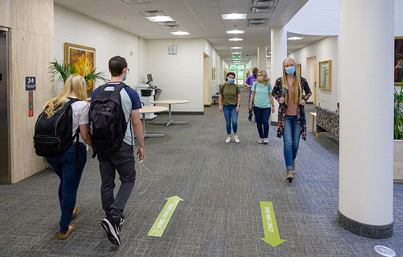 Student volunteers show the way to stay safe during this COVID 19 pandemic by social distancing, following pathway arrows and proper wearing of masks .