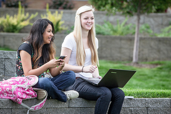 Two girls sit outside in the ampitheater on the first day of school