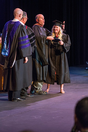 Brian Atkinson congratulate his daughter-in-law as she walks across the stage at convocation for the College of Performing and Visual Arts.