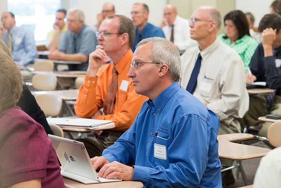 Faculty gather in the Hinckley Building at a Faculty Conference to share and learn from each other at the beginning of the 2013 Fall semester.