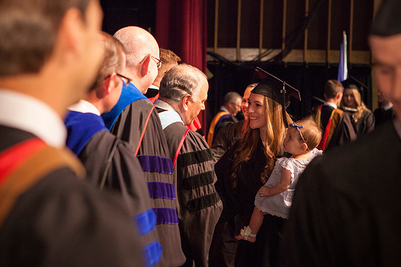 Graduate shakes hands with Elder Ronald A. Rasband at convocation for the College of Business and Communication.