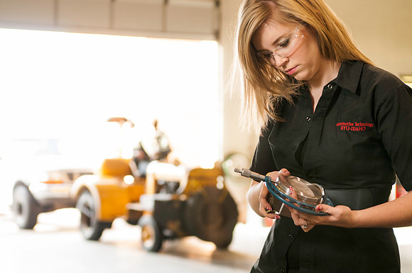 Student inspects engine parts in the Auto lab in the Austin building
