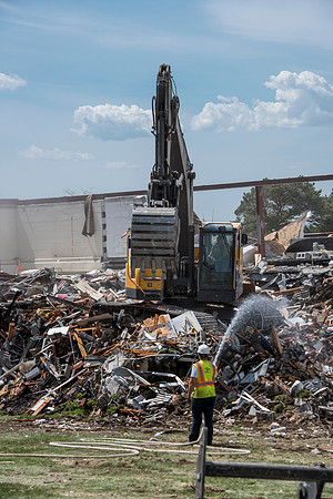 Construction workers work at tearing down the old campus dorms for a new campus project.