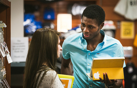 A man and woman talk to each other as they are purchasing textbooks at the University Bookstore