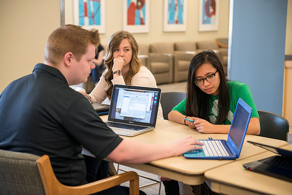 Zach Litchfield from the IT Department helps Sarah Nielsen and Dyna Santo with their computers.
