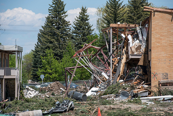 Construction workers work at tearing down the old campus dorms for a new campus project.