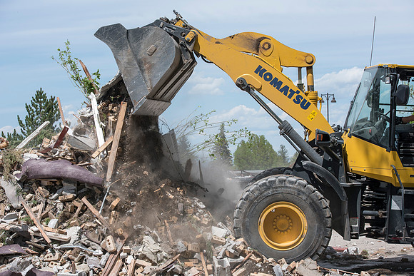 Construction workers work at tearing down the old campus dorms for a new campus project.