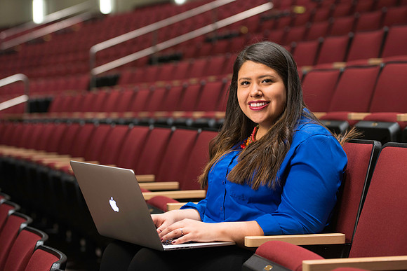 Christina Camano poses with a laptop in the balcony of the I-Center.