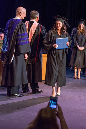 BYU-Idaho graduates accepting their diploma covers at convocation for the College of Perfoming and Visual Arts. Photo by Ryan Chase