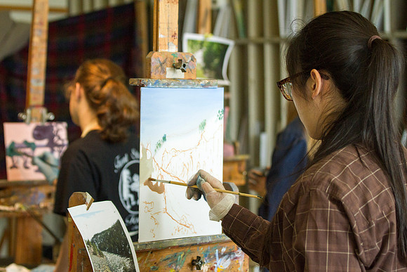 A student in Brother Bodily's Painting class begins to paint a beautiful landcape in the Spori Building.