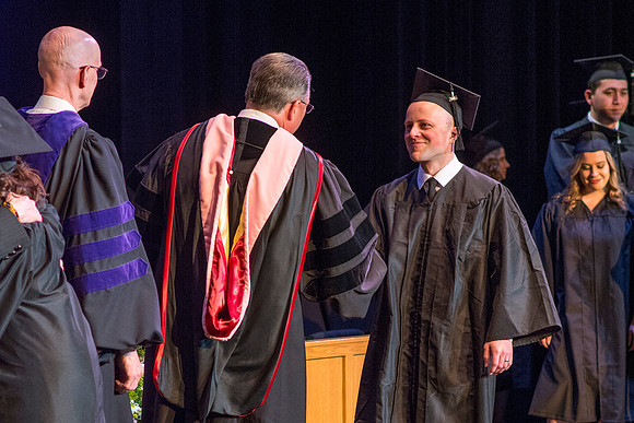 BYU-Idaho graduates accepting their diploma covers at convocation for the College of Perfoming and Visual Arts. Photo by Ryan Chase