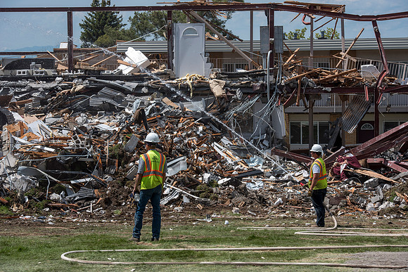 Construction workers work at tearing down the old campus dorms for a new campus project.