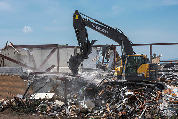 Construction workers work at tearing down the old campus dorms for a new campus project.