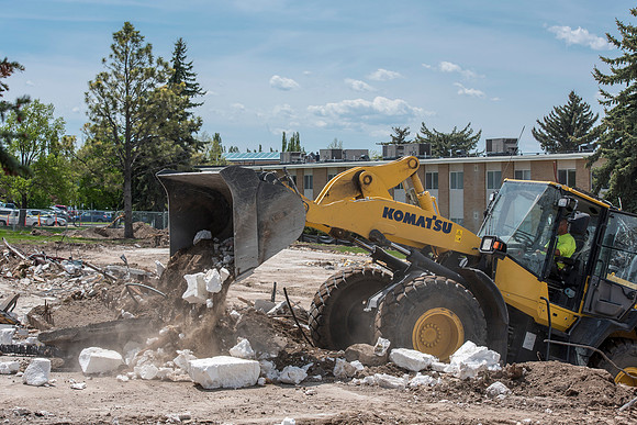 Construction workers work at tearing down the old campus dorms for a new campus project.