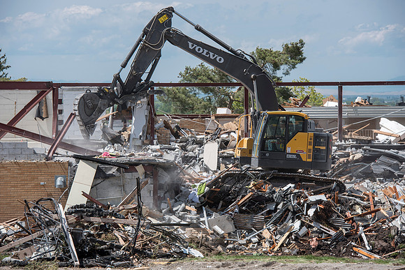 Construction workers work at tearing down the old campus dorms for a new campus project.