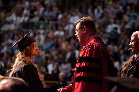 President Gilbert and Elder Ronald A. Rasband shake hands with graduates during convocation in the Hart Auditorium.