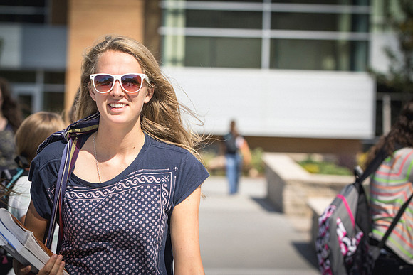 A woman smiles as she walks between classes on the first day of school