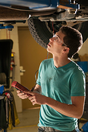 Student in auto lab, in the austin building inspects voltage on battery