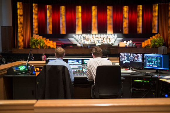 Josh Foster (in blue shirt) and student assistant control the Audio Visual Console on ground floor of the I-Center.
