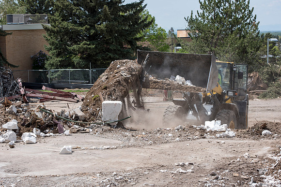 Construction workers work at tearing down the old campus dorms for a new campus project.